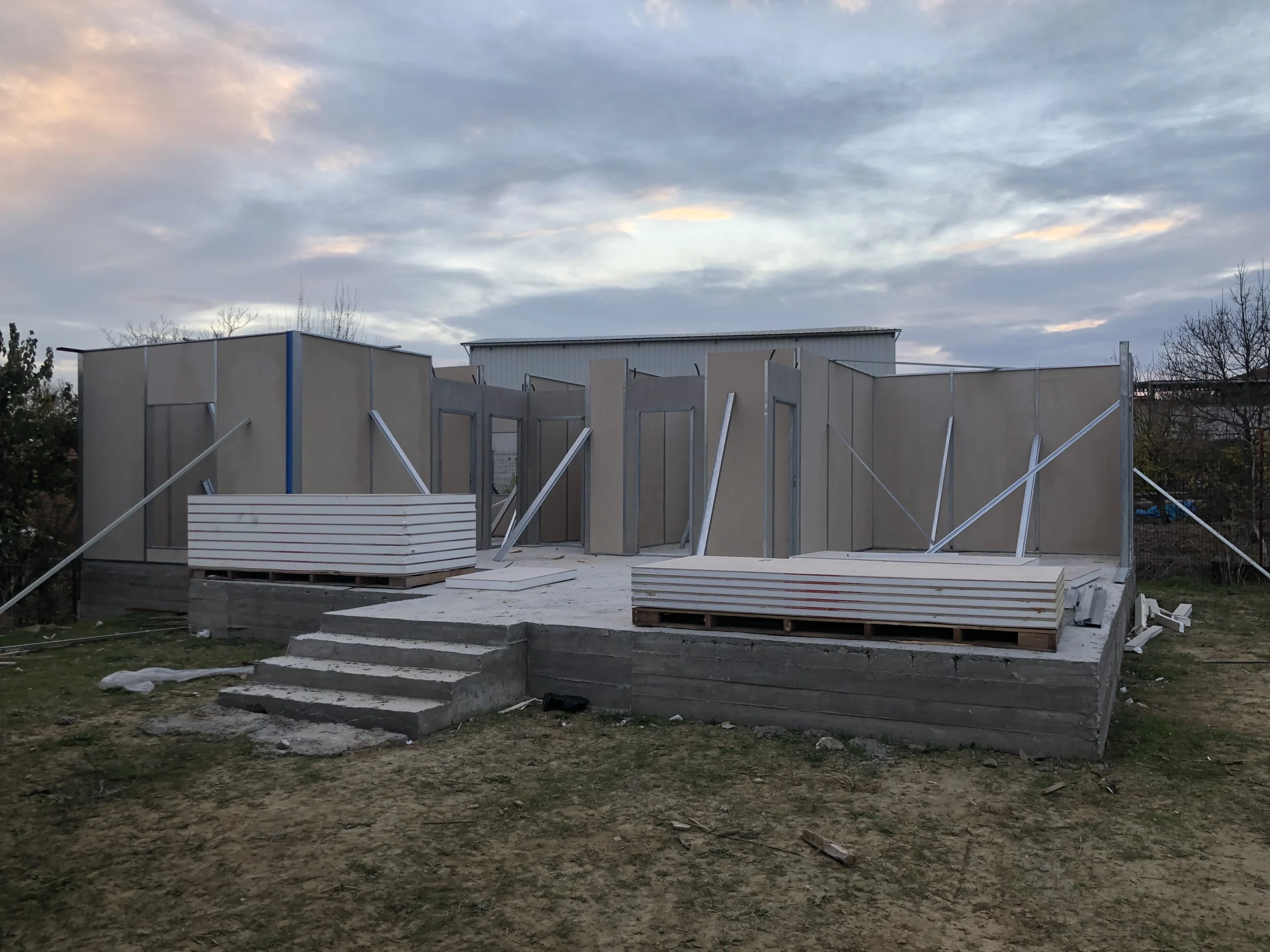 Prefabrik evin duvar panelleri monte edilmiş, çatı aşamasına hazırlanan yapı. Hızlı kurulum ve sağlam yapı sistemi.